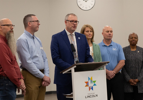 Jon Kisby, center, speaks at the podium during the Mayor's press conference.