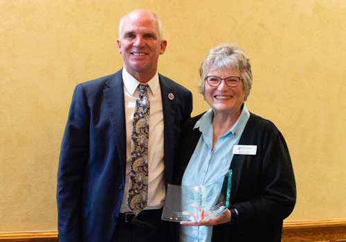 Dr. Paul Illich, SCC president, and Nancy Seim, SCC board of governors, smile as Seim holds NCCA Governors Award. 