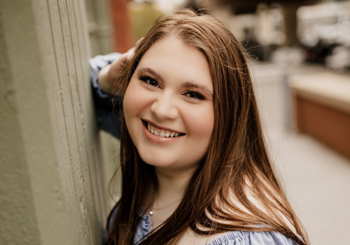 Kaylin Smith looking at the camera and smiling. She has auburn hair and brown eyes. 